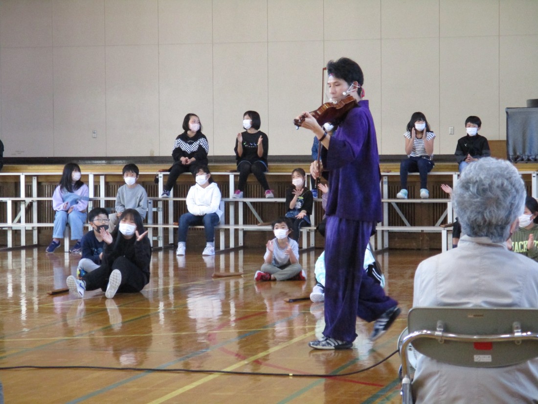 小学生たちの近くでバイオリンを演奏する様子